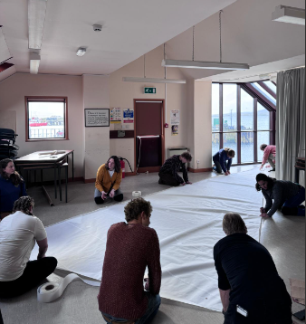 Eight people making a sail on the floor